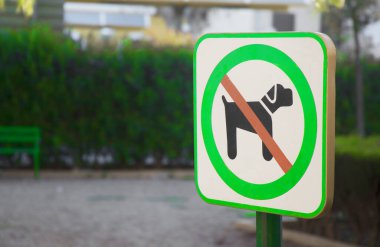 Parkta köpek yasağı tabelasını geçiyor