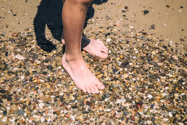 夏のビーチのぬれた石や砂の上の白い子供たちの裸の足 — ストック写真