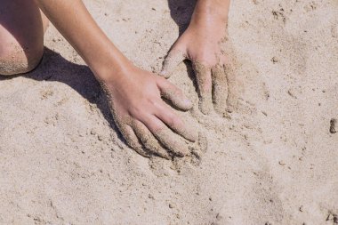 Çocukların elleri kumsalda oynuyor. Mektup koymak için yer var.