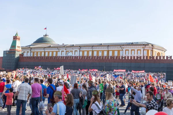 Procesión del Regimiento Inmortal en el Día de la Victoria: miles de personas marchan a lo largo de la Plaza Roja con banderas y retratos en conmemoración de sus seres queridos que lucharon en la Segunda Guerra Mundial — Foto de Stock