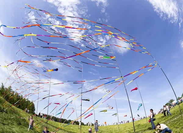 Fruwające w wiatr kolorowymi wstążkami i kolorowe latawce na festiwalu latawców z szczęśliwych ludzi i dzieci na całym — Zdjęcie stockowe