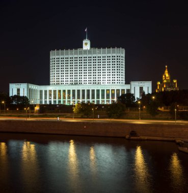 Rus beyaz evi (Rusya Federasyonu hükümeti) ünlüsü Stalin skyscaper Moskova'da arka planda gece ile. Renkli aydınlatma ve nehir yansımalar. Moscow, Rusya Federasyonu