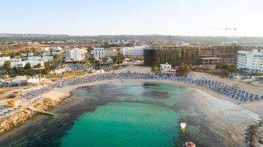 Vathia Gonia plajı, Ayia Napa, Famagusta, Kıbrıs 'ın havadan kuş bakışı görüntüsü. Gündoğumunda, Agia Napa 'da yaz tatillerinde altın kum, güneşlik, deniz restoranları ve deniz restoranlarıyla turistik bölge kayalık körfezi..