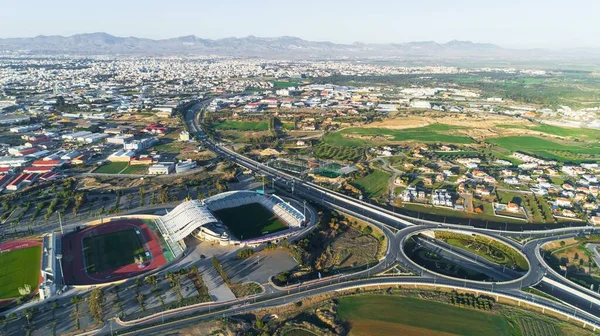 Aerial bird\'s eye view of GSP football stadium, highway A1 and round about at Latsia, Nicosia, Cyprus. The soccer field, athlete track, seats and auxiliary pitch of Pancyprian Gymnastic Association Stadium from above