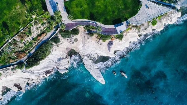 Simgesel Yapı büyük beyaz tebeşir rock Valilik Beach, Limasol, Kıbrıs hava görünümünü. Dik taş kayalıklarla ve derin mavi deniz dalgaları koyları ve Kalimnos balık restaurant yukarıdan yanındaki karanlık kum kırma.