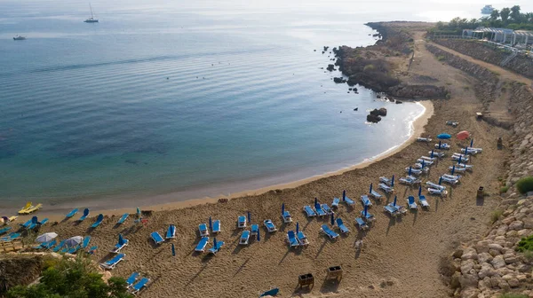 Aerial bird\'s eye view of Sirena beach in Protaras, Paralimni, Famagusta, Cyprus. The famous Sirina bay tourist attraction with sunbeds, golden sand, restaurant, people swimming in sea on summer holidays from above.