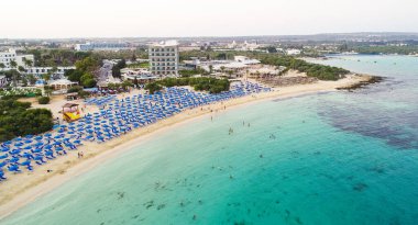Ünlü Makronissos sahil şeridi Ayia Napa, Famagusta, Kıbrıs 'ın havadan kuş bakışı manzarası. Günbatımında Agia Napa 'da altın kum, güneşlik, deniz restoranları ve yaz tatilleri ile turistik mekan Makronisos Körfezi..