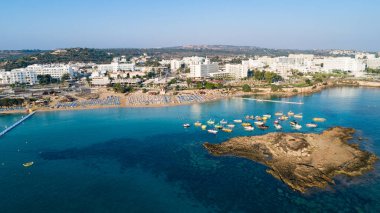 Protaras, Paralimni, Famagusta, Kıbrıs 'taki İncir ağaçlarının kuş bakışı görüntüsü. Ünlü turistik eğlence ailesi, tekneleri, güneşlikleri, restoranları, su sporları olan kumlu plajlar yaz tatillerinde denizde yüzen insanlar..