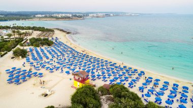 Ünlü Makronissos sahil şeridi Ayia Napa, Famagusta, Kıbrıs 'ın havadan kuş bakışı manzarası. Günbatımında Agia Napa 'da altın kum, güneşlik, deniz restoranları ve yaz tatilleri ile turistik mekan Makronisos Körfezi..