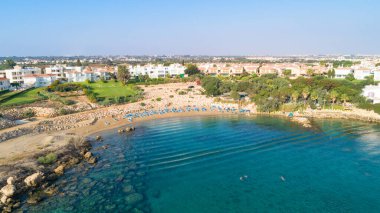 Protaras, Paralimni, Famagusta, Kıbrıs 'taki Sirena sahilinin kuş bakışı görüntüsü. Güneş yatakları, altın kum, restoran ve yaz tatillerinde insanların denizde yüzdüğü ünlü Sirina Körfezi turistik merkezi..