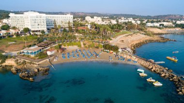 Protaras, Paralimni, Famagusta, Kıbrıs 'taki Green Bay' in havadan kuş bakışı görüntüsü. Ünlü turist eğlencesi dalış yeri kayıklar, güneşlikler, restoranlar, su sporları, yaz tatillerinde denizde yüzen insanlar, yukarıdan.