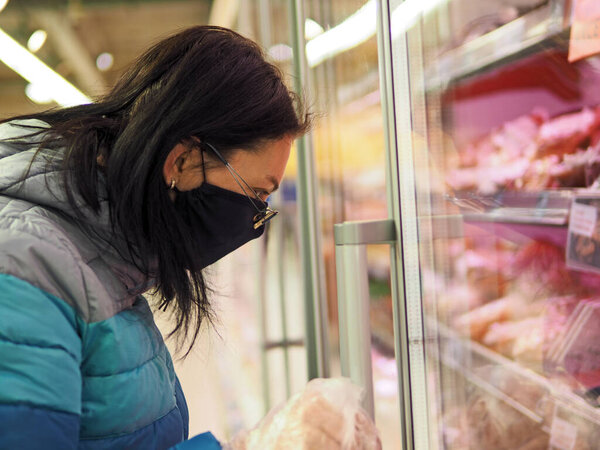 женщина в защитной маске на лице покупает в торговом центре во время пандемии коронавира
