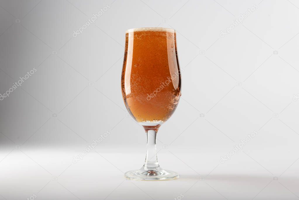 A full beer glass containing golden ale set against a clean background