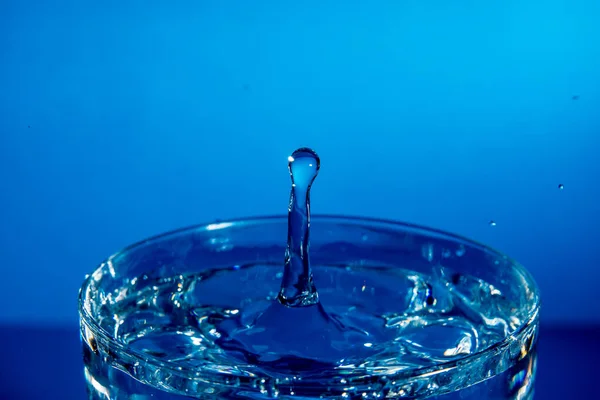 Drop of water falling into a glass, hitting water surface.Selected focus — ストック写真