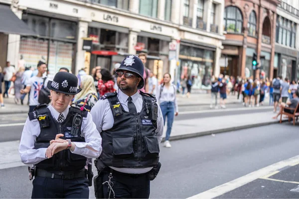 Londres, Reino Unido, julio de 2019. Dos policías británicos patrullando las calles de Inglaterra con chalecos antipuñaladas. Oxford Street. Enfoque seleccionado — Foto de Stock