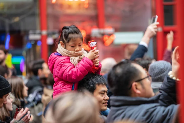 London den 26 januari 2020. En leende ung flicka som sitter på sina fäders axlar medan hon går genom en folkmassa i Chinatown. Nyårsfirande — Stockfoto