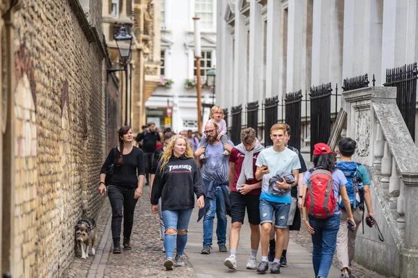 Cambridge, İngiltere, 1 Ağustos 2019. Kings Koleji önünde güneşli bir günde Cambridge caddesinde yürüyen ve fotoğraf çeken turistler