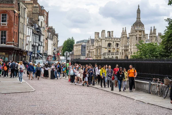 Cambridge, İngiltere, 1 Ağustos 2019. Kings Koleji önünde güneşli bir günde Cambridge caddesinde yürüyen ve fotoğraf çeken turistler