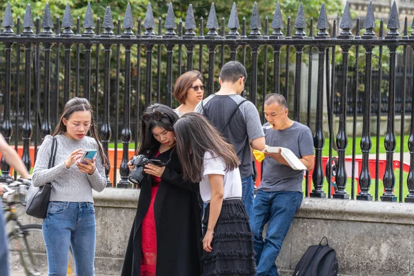 Cambridge, İngiltere, 1 Ağustos 2019. Kings Koleji önünde güneşli bir günde Cambridge caddesinde yürüyen ve fotoğraf çeken turistler