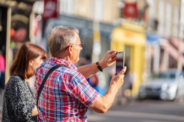 Cambridge, İngiltere, 1 Ağustos 2019. Kings Koleji önünde güneşli bir günde Cambridge caddesinde yürüyen ve fotoğraf çeken turistler