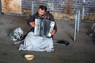 Londra, Ingiltere, Temmuz, 2019. Evsiz adam akordeon oynuyor