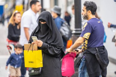 Londra, Ingiltere, Temmuz, 2019. Londra 'da bir Müslüman kadın bir niqab giyen, cep telefonu kullanarak alışveriş yaparken. Oxford Caddesi