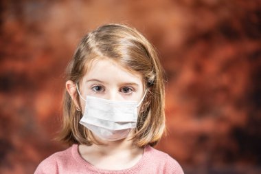 Coronovirus Karantina, Evde Kal Konsepti. Covid-19 salgını. Cerrahi maske takan küçük kız.