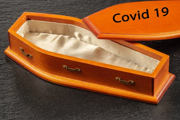 Inscription COVID-19 on coffin lid near empty wooden coffin. Coronavirus disease concept