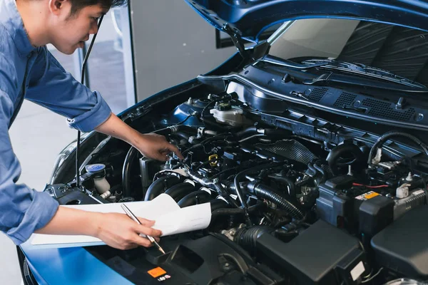 Asian Man mechanik kontroli pisanie notatki na schowku.Blue samochód — Zdjęcie stockowe