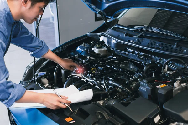 Asian Man mekaniker inspektion skriva lapp på Urklipp. Blå bil — Stockfoto