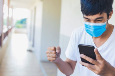 Asyalı adam cerrahi maske takıyor. Akıllı telefon haber bülteni covid 19 'u durdurun. Ondokuz virüs covid-19 ya da corona korunuyor.