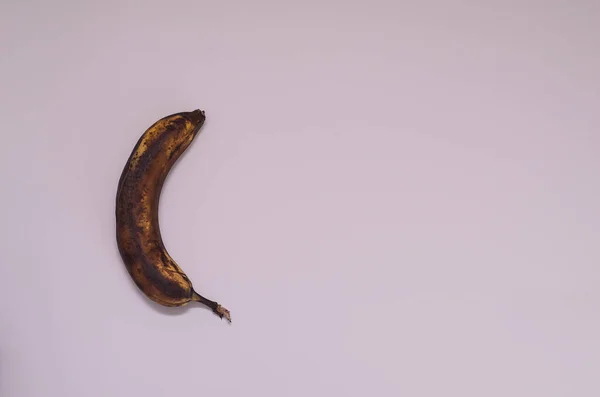 Ugly food. Dark banana spoiled over time on a white background. Horizontal orientation, caps lock.