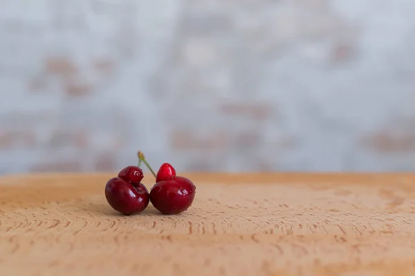 Ugly organic fruits - sweet cherries on a brown board. Trends. Ugly food. Copy space. Horizontal orientation.