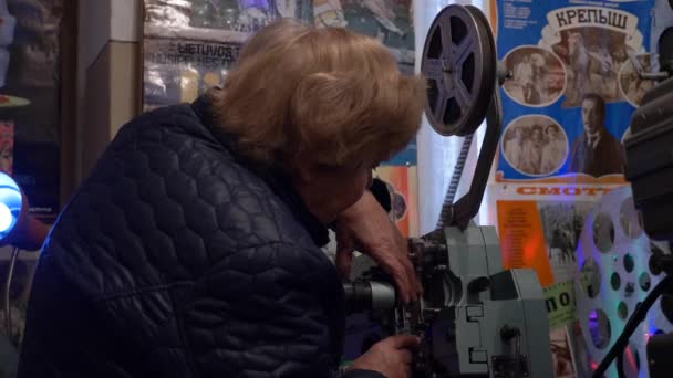 Közelkép egy idős nőről, aki nosztalgiázva próbál bekapcsolni egy hosszú távon nem használt filmvetítőt. — Stock videók