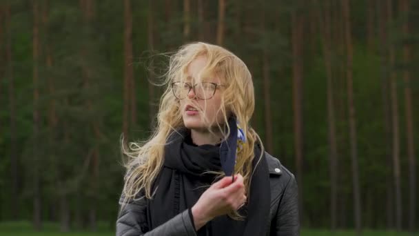Жінка знімає маску для обличчя. Молода блондинка глибоко дихає в лісі. Чуттєвий момент, вітер трясе її волосся . — стокове відео