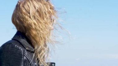 İskandinav görünüşlü kadın denize bayılıyor. Rüzgar saçlarını sallar..