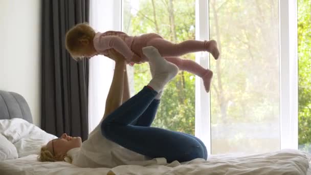 Vacker lycklig kvinna leker med småbarn flicka. Systrar ler mot varandra, familj. — Stockvideo