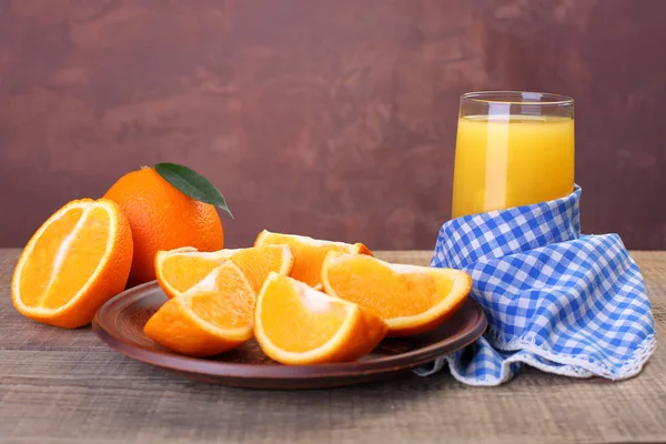 Orangensaft im Glas mit frischen Früchten auf Holzgrund — Stockfoto