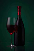Láhev červeného vína a skla na zelené 