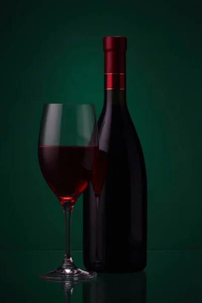 Garrafa de vinho tinto e vidro em verde — Fotografia de Stock