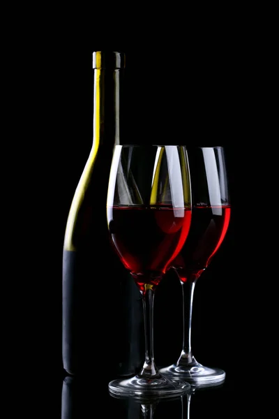 Copa y botella de vino con vino tinto aislado en negro — Foto de Stock