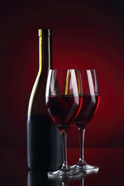 Copa de vino y botella con vino tinto sobre tinto — Foto de Stock