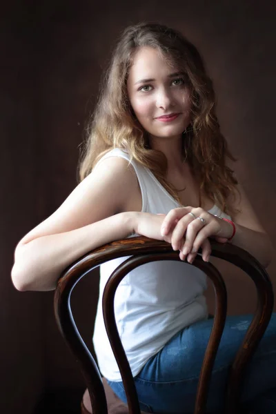 Atrakcyjny brunetka dziewczyna siedzi na krześle przez brown — Zdjęcie stockowe