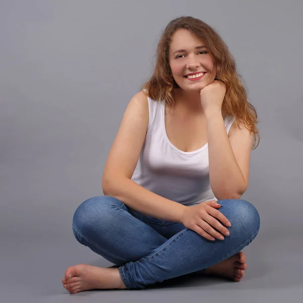 Pretty young girl sitting on gray — Stock Photo, Image