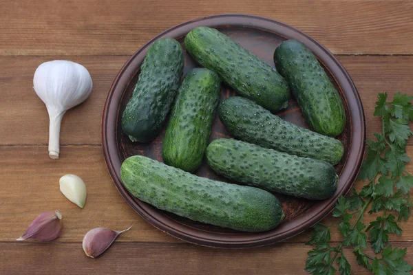 Cucumbers in plate on wood background — Stock Photo, Image