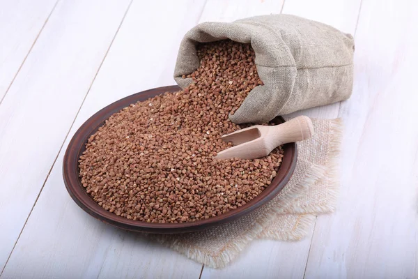 Buckwheat in sack with wooden scoop — Stock Photo, Image