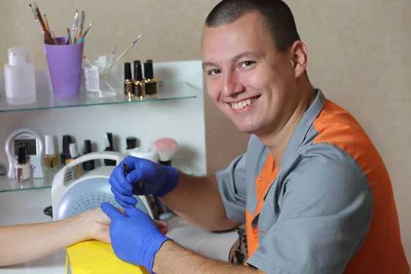 Smiling master of manicure is making manicure