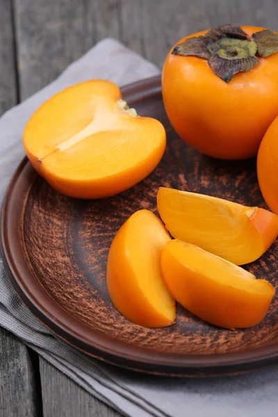 Japanese persimmons in ceramic plate. Closeup — Stock Photo, Image