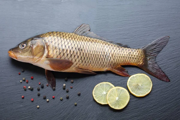 Fresh carp on black cutting board — Stock Photo, Image