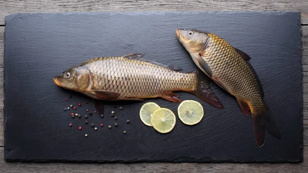 Fresh carps on black cutting board — Stock Photo, Image